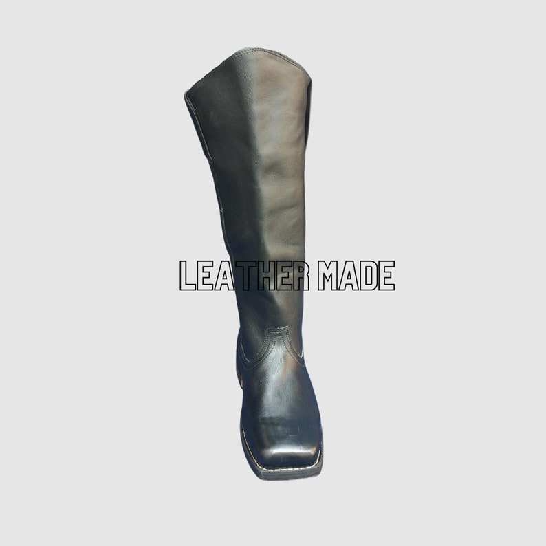 May include: A tall black leather boot with a square toe and a visible stitched welt. The boot features a smooth shaft and a structured heel. The text LEATHER MADE is displayed in white capital letters with a black outline across the center.