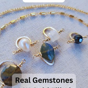 May include: Three gold filled sterling silver jewelry connectors with real gemstones. The connectors feature a white pearl, a clear moonstone, and a dark green labradorite gemstone. The text on the image reads 'The Most Unique Permanent Jewelry Connectors' and 'Real Gemstones 14K Gold Filled Sterling Silver'.