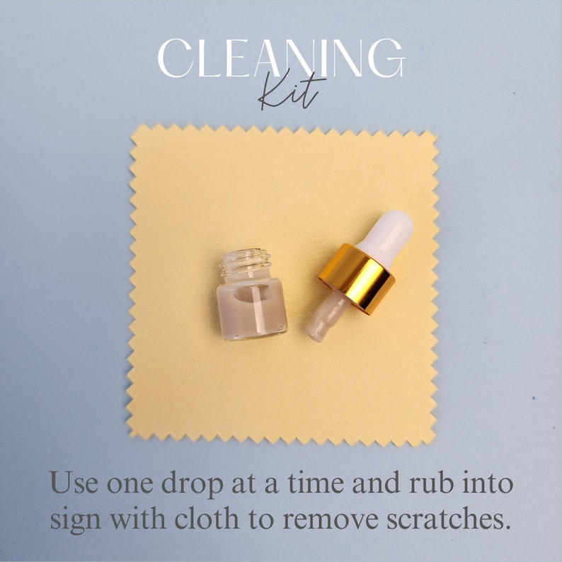 May include: A cleaning kit for removing scratches from signs. The kit includes a small bottle of cleaning solution and a cloth. The bottle has a dropper and is made of clear glass with a gold cap. The cloth is beige and has a textured surface.