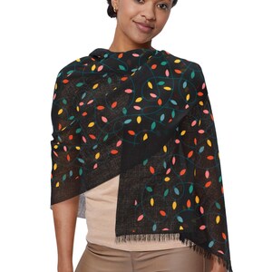 May include: A black scarf with a colorful leaf pattern in red, yellow, pink, and teal. The scarf has a fringed edge and is draped over the shoulders.