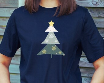 May include: Navy blue t-shirt featuring a Christmas tree design. The tree is composed of three sections in white, green, and olive green, adorned with snowflakes and topped with a yellow star. The shirt is made of a soft material.