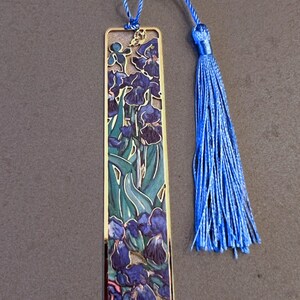 May include: A gold-colored bookmark with a blue tassel. The bookmark features a colorful image of irises and the text "Van Gogh".