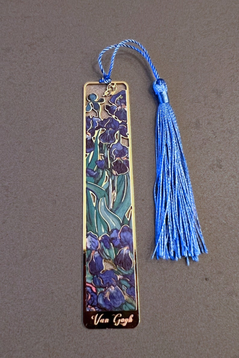 May include: A gold-colored bookmark with a blue tassel. The bookmark features a colorful image of irises and the text "Van Gogh".