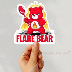 May include: A red cartoon bear with a fiery halo and a spoon in its hand. The bear is standing on cracked ground with flames around it. The text "FLARE BEAR" is written below the bear.