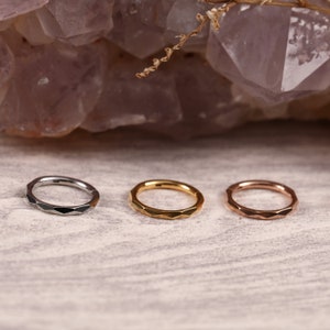 Könnte beinhalten: Drei nahtlose Ringe in verschiedenen Farben mit einer facettierten Kante. Die Ringe sind silber, gold und roségold.