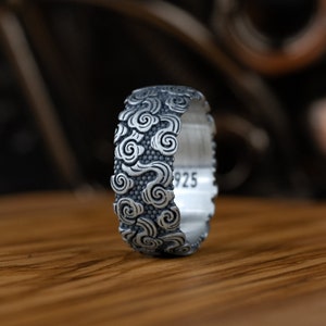 Può includere: Un anello d'argento con un design a nuvola dettagliato. L'anello è contrassegnato con "925" all'interno.