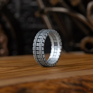 Könnte beinhalten: Ein silberner Ring mit einem strukturierten Design, das einem Reifenprofil ähnelt.