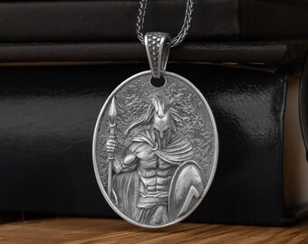 May include: Silver pendant necklace featuring a detailed depiction of a warrior holding a spear and shield. The pendant is round and has a textured surface.