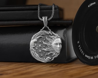 May include: A silver pendant necklace featuring a detailed design of a woman's face with flowing hair, a crescent moon, and stars. The pendant is on a silver chain.