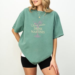 May include: A green t-shirt with a pink martini glass graphic and the text "Save water drink martinis".
