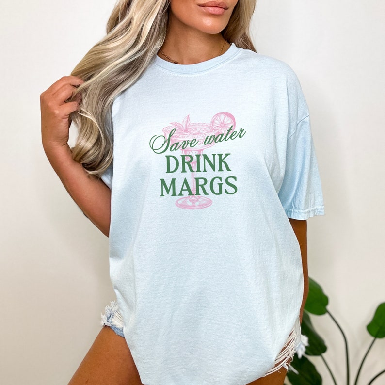 May include: Light blue t-shirt with a green and pink margarita graphic and the text "Save water drink margs".