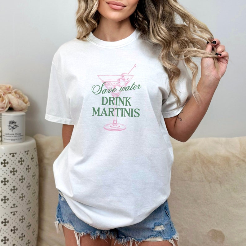 May include: White t-shirt with a pink martini glass graphic and the text "Save water drink martinis" in green.