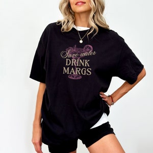 May include: Black oversized t-shirt with a pink margarita glass graphic and the text "Save water drink margs".