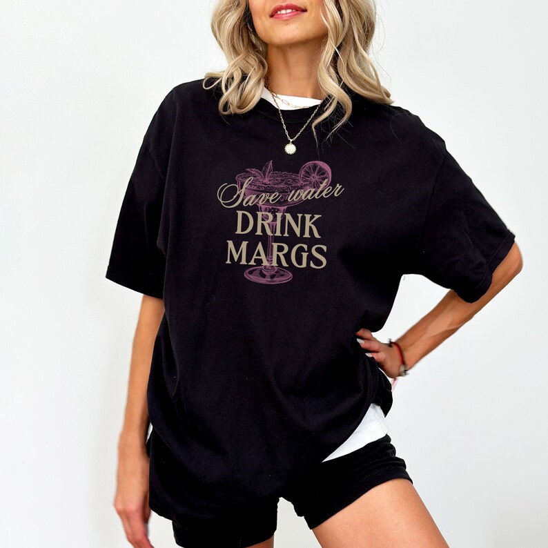 May include: Black oversized t-shirt with a pink margarita glass graphic and the text "Save water drink margs".