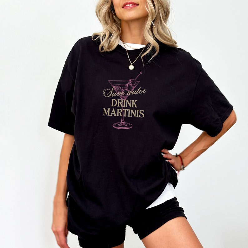 May include: Black oversized t-shirt with a pink martini glass graphic and the text "Save water drink martinis".