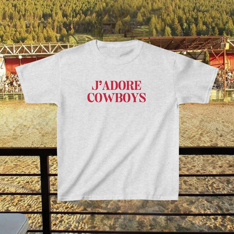 May include: A gray t-shirt with the text "J'ADORE COWBOYS" printed in red.