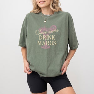 May include: A green t-shirt with the text "Save water drink margs" and a pink margarita glass graphic.