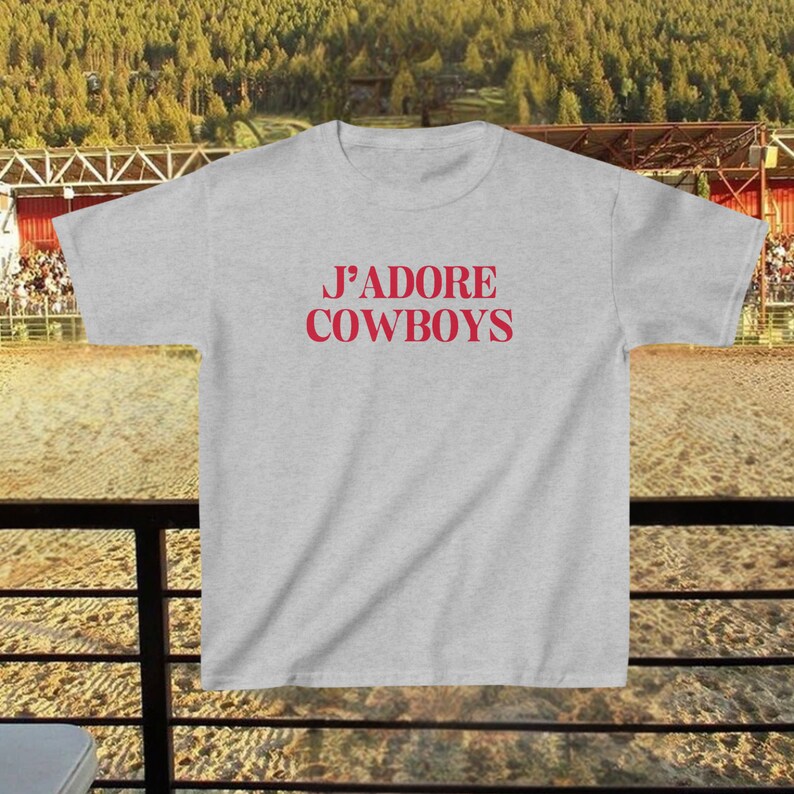 May include: A gray t-shirt with the text "J'ADORE COWBOYS" printed in red on the front.