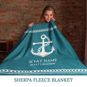 May include: Teal sherpa fleece blanket with a white anchor and chain design. The blanket has a white border with a chain pattern. The text "BOAT NAME BOAT LOCATION" is printed in white below the anchor.