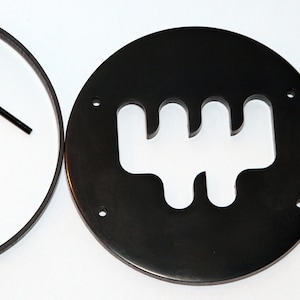 May include: A black metal gear shift knob with a cut-out design for a manual transmission. The knob comes with a black rubber ring and four black screws.