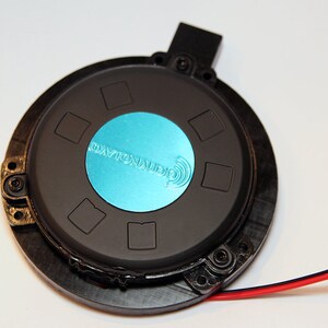 May include: A black speaker driver with a blue Dayton Audio logo. The driver has a black frame and a black centre with a blue circle in the centre. The driver is connected to a red and black wire.