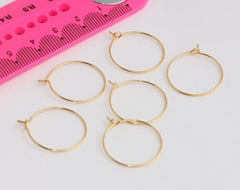 May include: Five gold hoop earrings on a white surface. The earrings are approximately 1 inch in diameter.