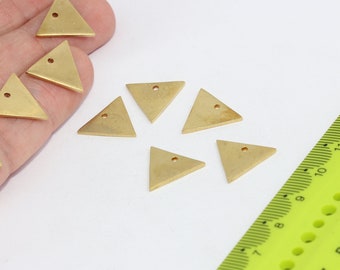 May include: A collection of small, gold-colored triangle charms with a single hole at the top of each. A neon green ruler is in the background. These charms are likely for jewelry making or other craft projects.