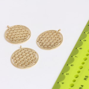 May include: Three gold-coloured metal charms featuring a geometric flower of life design. The charms are round and have a hole at the top for hanging.