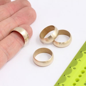 May include: Four gold-coloured metal rings of varying sizes, with a ruler in the background.