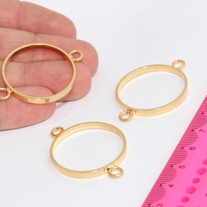 Puede incluir: Tres biseles metálicos dorados en formas redondas y ovaladas, cada uno con pequeños bucles para fijar. Una regla rosa en el fondo sirve de escala. Ideal para la fabricación de joyas.