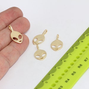 Peut inclure: Quatre breloques tête d'extraterrestre de couleur dorée avec une boucle pour les attacher à des bijoux. Les breloques mesurent environ 1,5 cm.