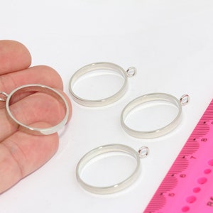 May include: Four silver-toned metal rings with a small loop at the top. The rings are approximately 1 inch in diameter and are arranged on a white surface.
