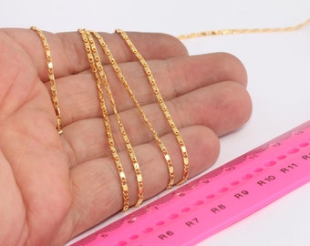 Puede incluir: Primer plano de un collar de cadena de oro con un patrón de eslabones cuadrados. La cadena se coloca sobre una mano y se mide con una regla rosa marcada con pulgadas y las letras R1-R13.