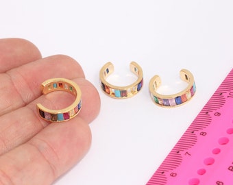 May include: Three gold ear cuffs with a rainbow of colorful stones. The ear cuffs are open and ready to be worn.
