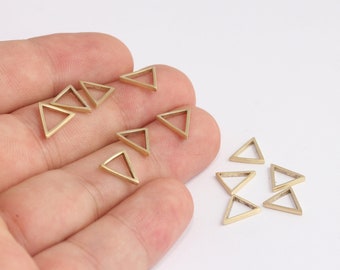 May include: A collection of small, gold-coloured triangle charms. The charms are arranged in a hand and on a white surface.
