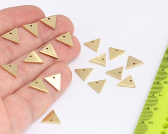 May include: A collection of 15 gold-coloured triangle-shaped metal charms with a hole at the top. The charms are scattered on a white surface.