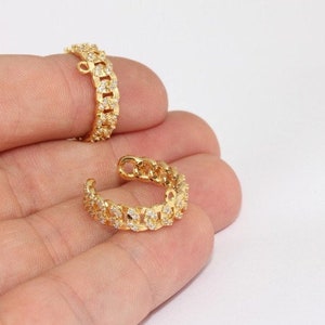 May include: Two gold-toned ear cuffs with a chain link design and clear cubic zirconia stones.