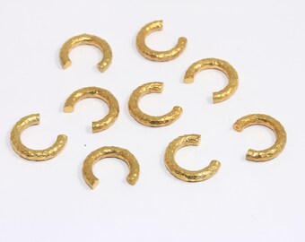 May include: Ten gold-colored metal hoops with a hammered texture. The hoops are all the same size and shape.