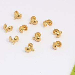 May include: Ten gold-toned metal bead caps, each with a small loop for attaching to a cord or chain. The caps are designed to be used as end caps for necklaces, bracelets, or other jewelry.