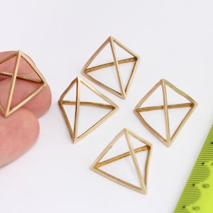 Può includere: Cinque forme di piramide geometriche in metallo dorato, ciascuna con una base quadrata e quattro lati triangolari. Le piramidi sono disposte a semicerchio su una superficie bianca.