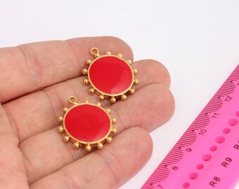 May include: Two gold-toned metal charms with red enamel round centers. The charms have a circle of small gold beads around the edge.