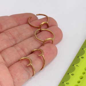 以下が含まれることがあります： 異なるサイズの4つの金の三日月リング。リングは、定規を背景に手に表示されています。