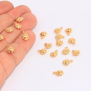 Può includere: Una collezione di 18 ciondoli a forma di sole in metallo dorato. I ciondoli sono piccoli e hanno un design in rilievo testurizzato. Sono perfetti per aggiungere un tocco di fantasia ai progetti di gioielleria.