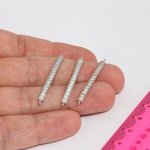 Può includere: Tre connettori a barra argentati con decorazioni in cristallo trasparente. Le barre sono lunghe circa 2,5 cm.