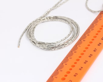 May include: A silver chain necklace with a box chain design. The chain is laid out on a ruler with orange markings and black numbers. The chain is approximately 10 inches long.
