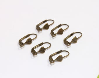 May include: Six antique gold-toned earring hooks with a heart-shaped design. The hooks are made of metal and have a smooth finish.
