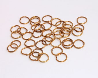May include: A pile of gold-colored jump rings, a type of metal ring used in jewelry making.