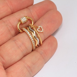 Peut inclure: Un ensemble de cinq bagues en or et en argent avec des accents de diamants. Les bagues sont empilées sur un doigt et présentent un charme en forme de cœur.