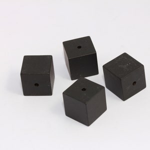 May include: Four black wooden cubes with a hole in the center of each cube.