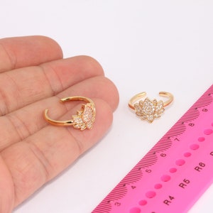 May include: Two gold-toned rings featuring a lotus flower design. The rings are embellished with clear cubic zirconia stones.